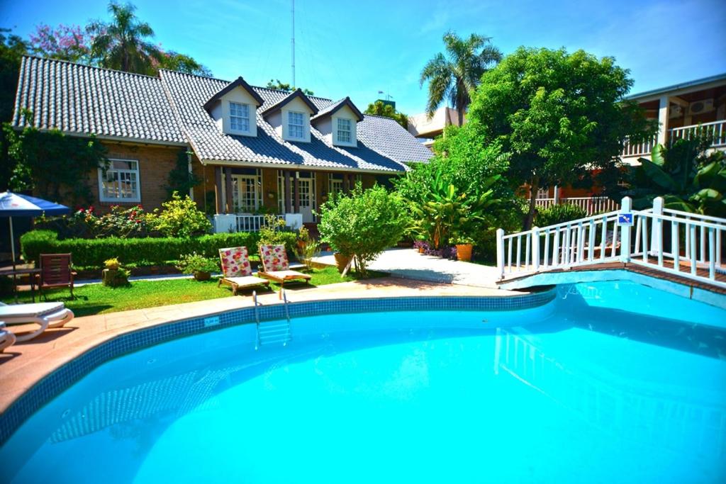 a large swimming pool in front of a house at Hotel Posada La Sorgente in Puerto Iguazú