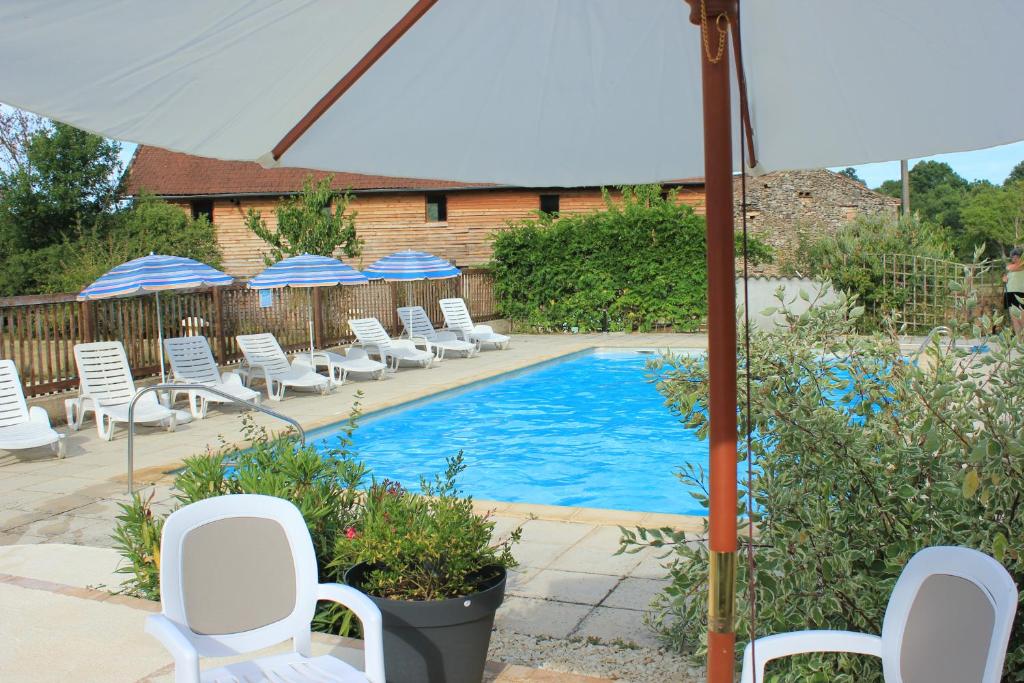 a swimming pool with white chairs and umbrellas at Gîtes de Peyrounou in Lacapelle-Biron