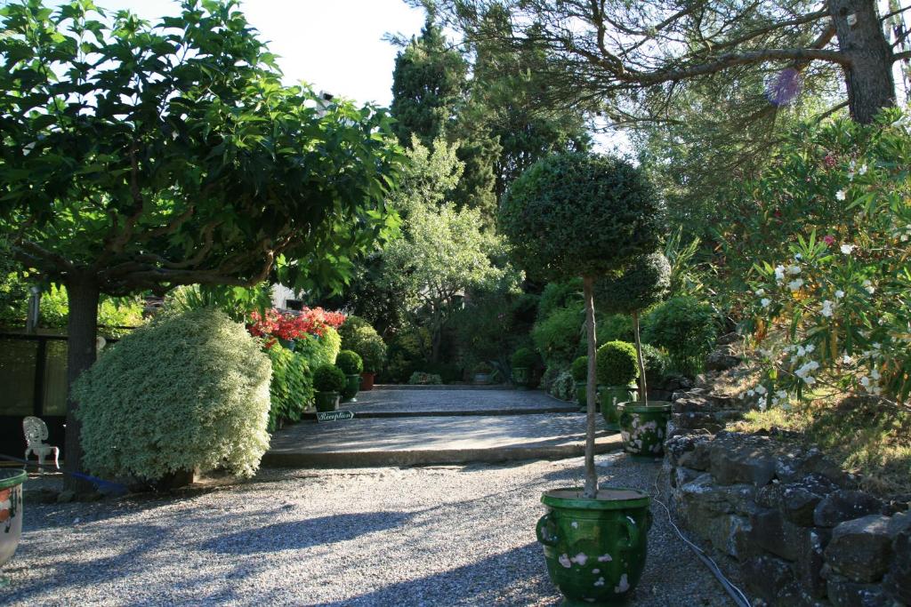 un jardín con muchos arbustos y árboles y una pasarela en La Maison sur la Colline, en Carcassonne