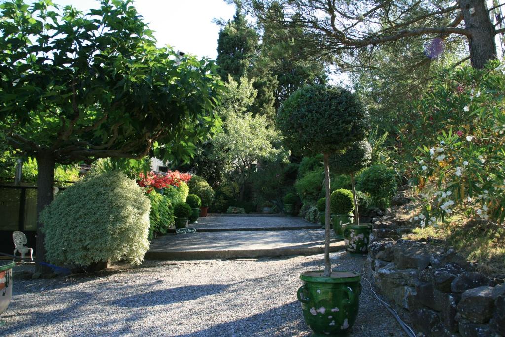 a garden with many bushes and trees and a walkway at La Maison sur la Colline in Carcassonne