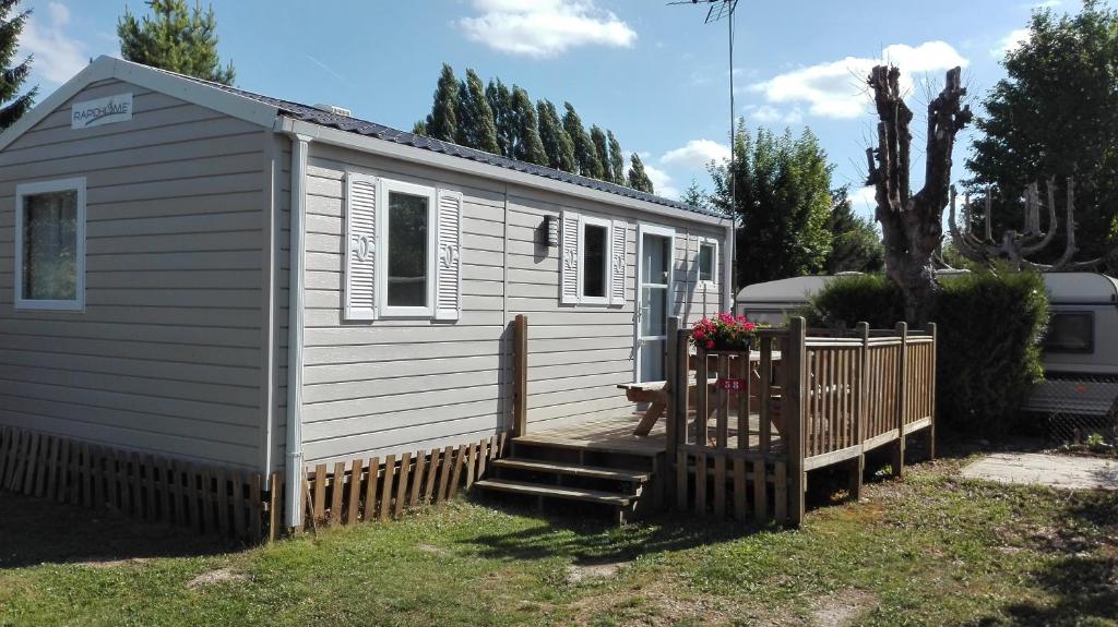 uma pequena casa branca com uma cerca de madeira em Camping Loisirs Des Groux em Mousseaux-sur-Seine