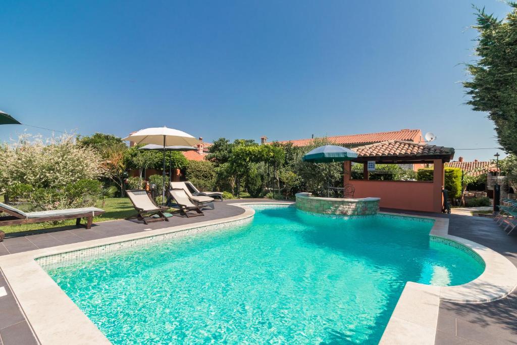 a swimming pool with two chairs and a gazebo at Country House Apartments in Pula