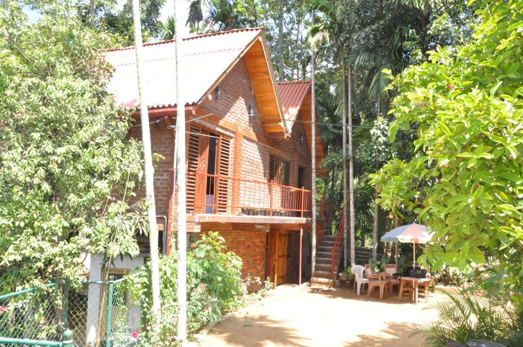 a wooden house with a table and an umbrella at Dew Lee Homestay in Ella