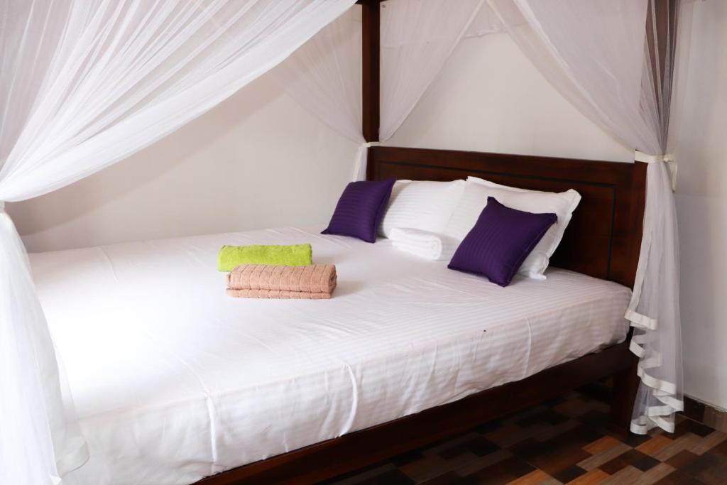 米瑞莎的住宿－Mirissa Gold Rush Villa，一间卧室配有白色床和紫色及绿色枕头