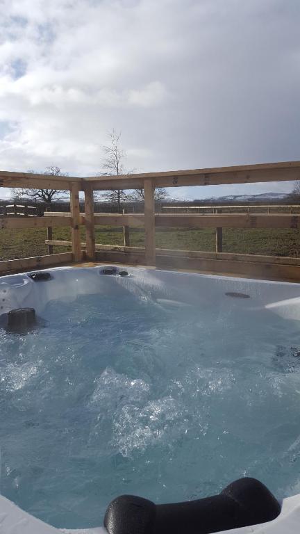 a hot tub with blue water in front of a fence at Ruth's Repose in Shrewsbury