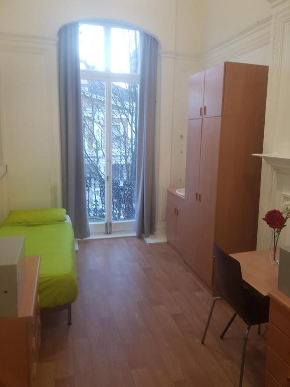 een kamer met een groen bed en een groot raam bij Railton House (Paddington) in Londen