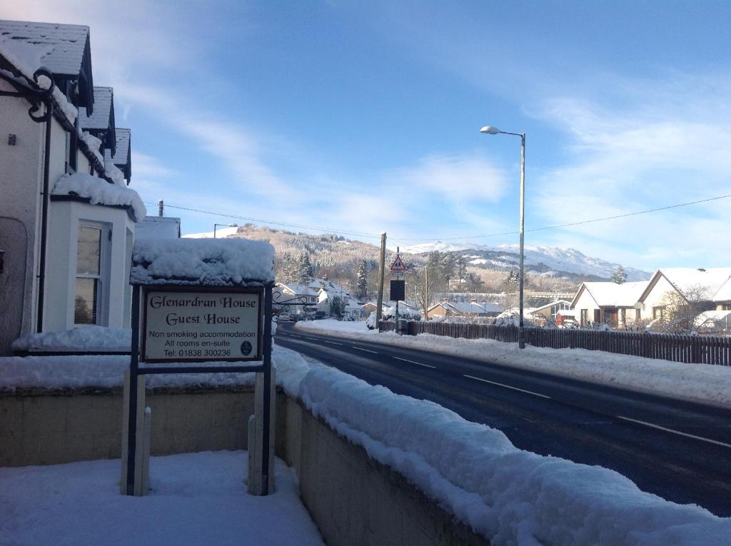 a sign on the side of a street covered in snow at glenardran house in Crianlarich