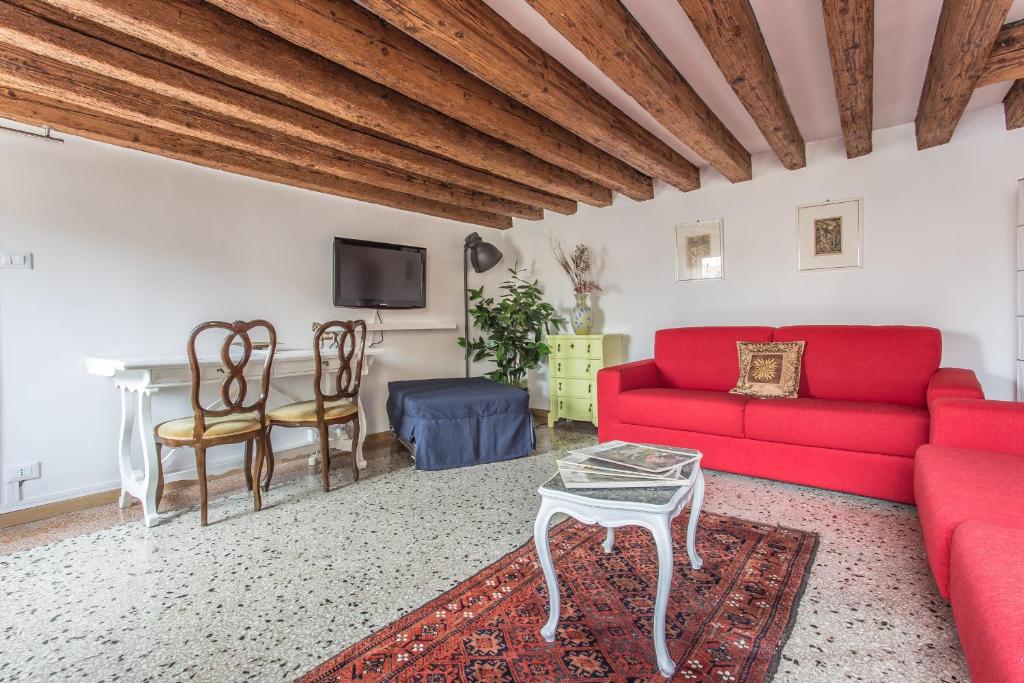 een woonkamer met een rode bank en een tafel bij Ca' Roberta in Venetië