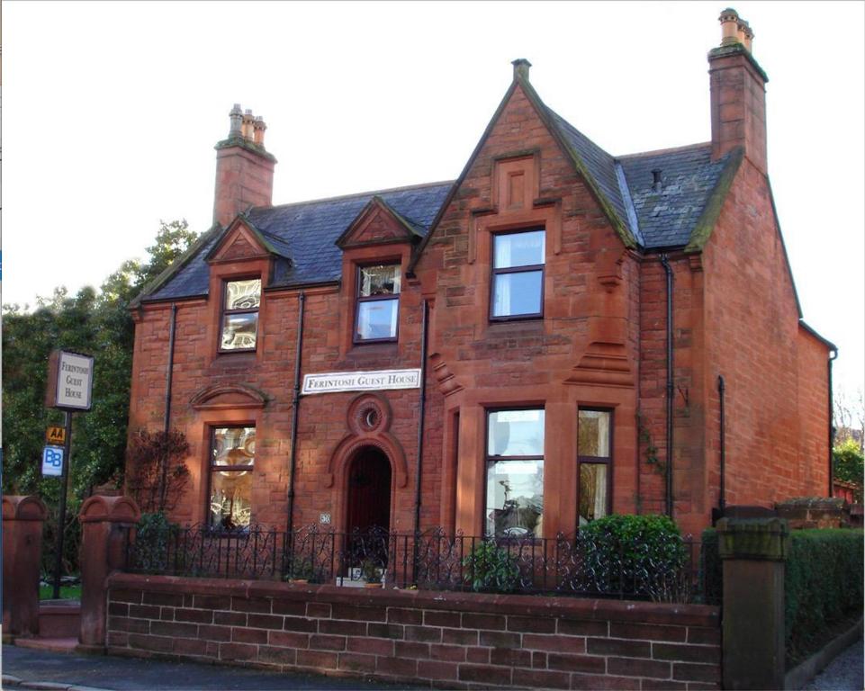 a red brick building with a black roof at Ferintosh Guest House in Dumfries