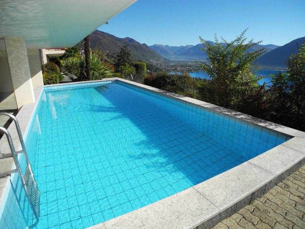 uma piscina azul com vista para a água em Pendio del Sole App 3838 em Orselina