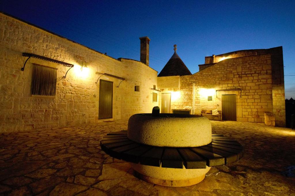 a building with a fountain in a courtyard at night at Maison MilleOttocento in Cisternino