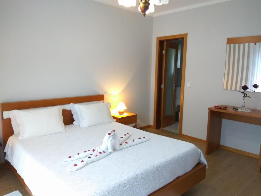 a bedroom with a white bed with a pair of shoes on it at ALojamento Costa da Banga in Geres