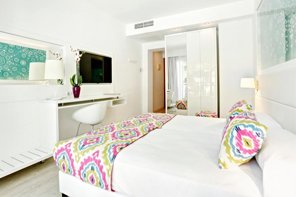 a white bedroom with a white bed and a desk at Grupotel Ibiza Beach Resort - Adults Only in Portinatx