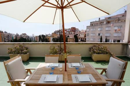 drewniany stół z krzesłami i parasol na balkonie w obiekcie ÁTICO DUPLEX CON VISTAS AL FORO ROMANO w mieście Tarragona