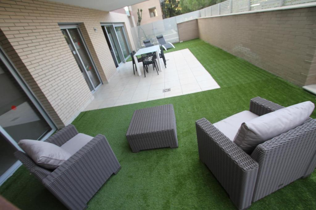 een patio met stoelen en een tafel op een gazon bij For a Stay Aqquaria Deluxe in Salou