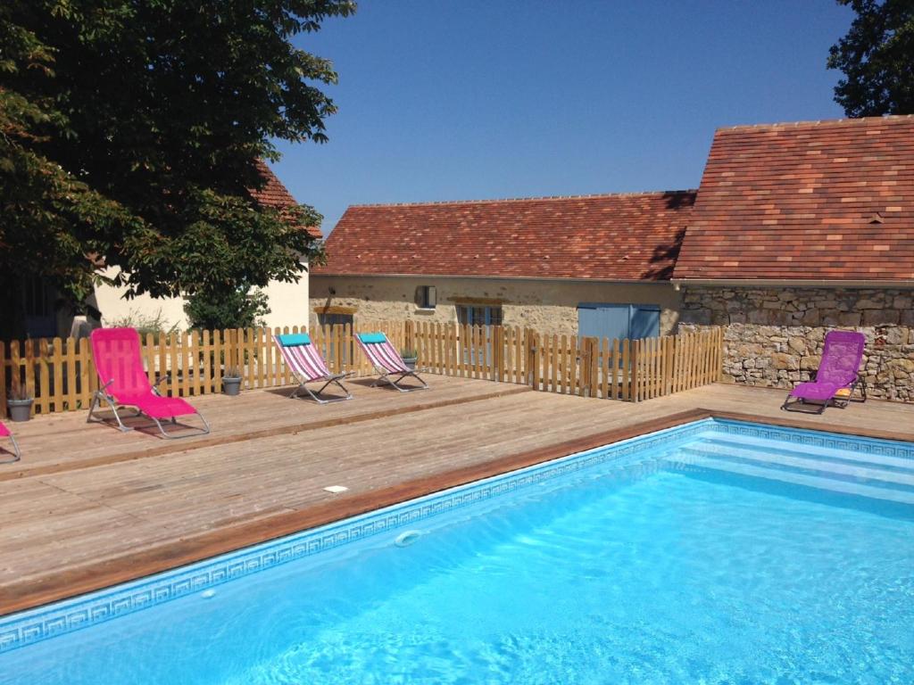 een zwembad met stoelen en een houten terras bij La Grange in Le Vigan
