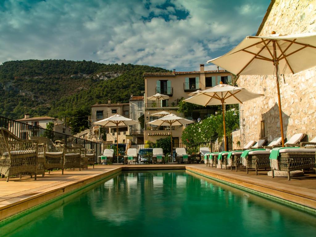 a swimming pool with chairs and umbrellas at Auberge De Tourrettes in Tourrettes-sur-Loup