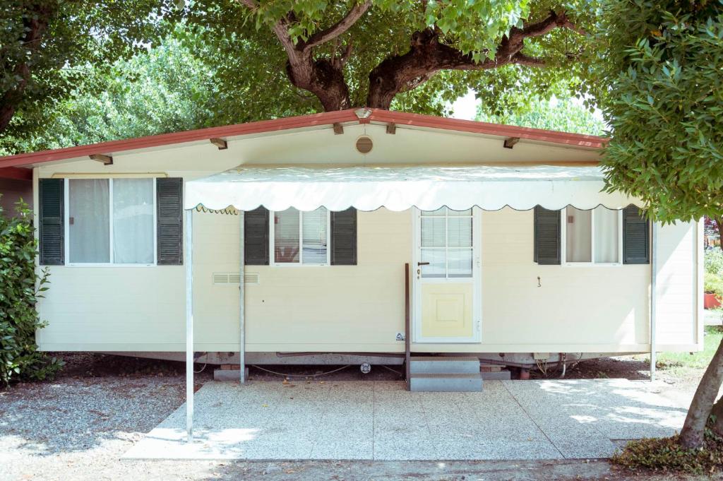 a white house with a tree in front of it at Camping Wien in Peschiera del Garda