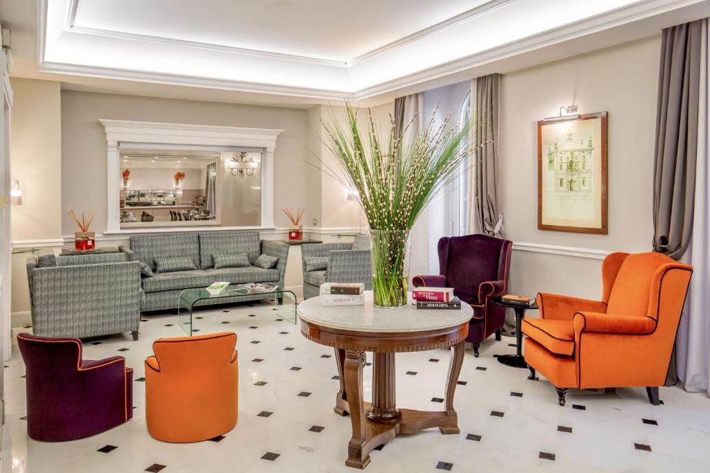 a living room with orange chairs and a table at Ludovisi Palace Hotel in Rome
