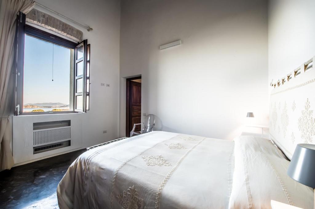a white bedroom with a large bed and a window at Faro Capo Spartivento in Chia