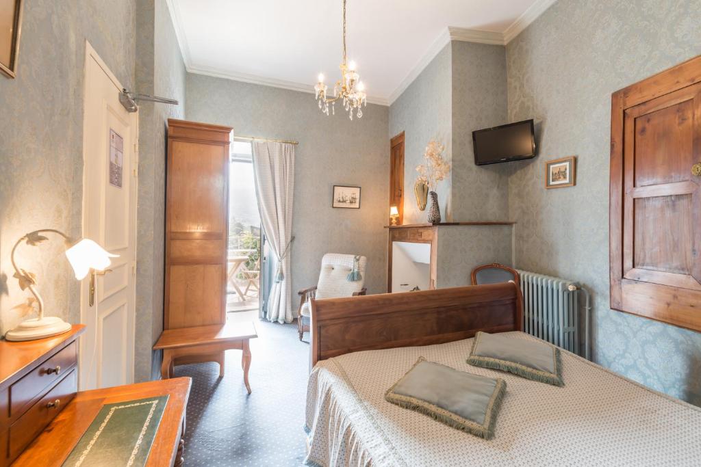 a bedroom with a bed and a table and a television at Logis Hôtel Beau Site in Argelès-Gazost