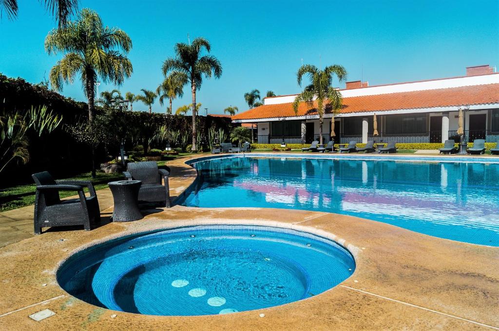 una gran piscina con palmeras y un edificio en Hotel Ecce Inn & Spa en Silao