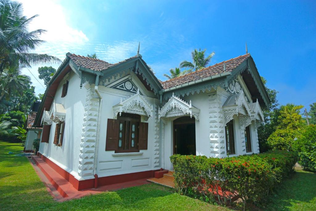 a small white house with a green yard at Old Parkland Hostel in Galle