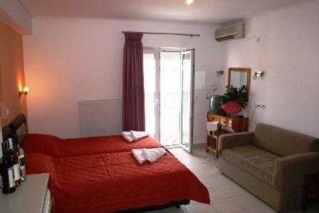 a bedroom with a red bed and a couch at Aria Hotel Samos Town in Samos