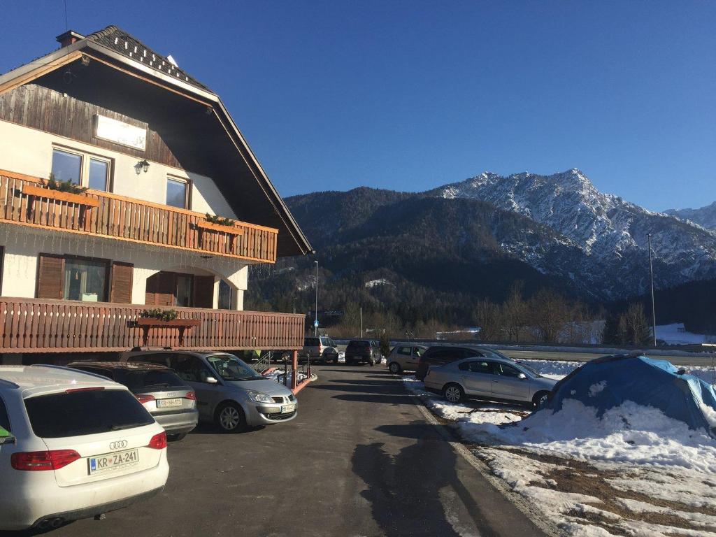 a building with cars parked in a parking lot with mountains at gostišče uh- planica in Rateče