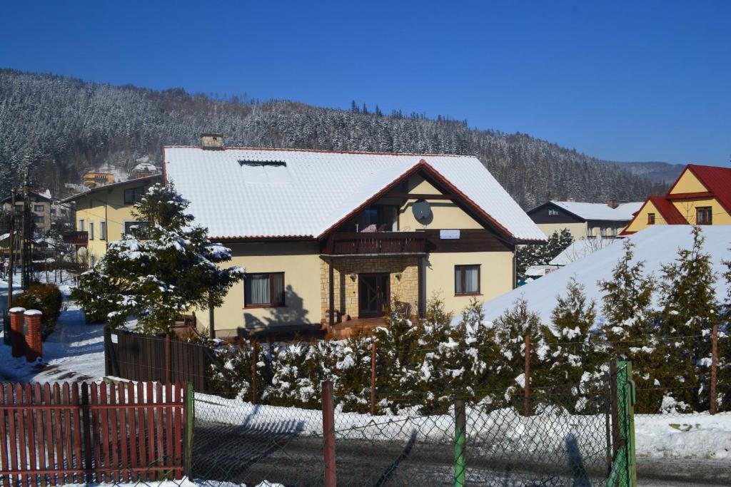 ein Haus mit Weihnachtsbäumen im Schnee in der Unterkunft Apartament Jodłowy in Szczyrk