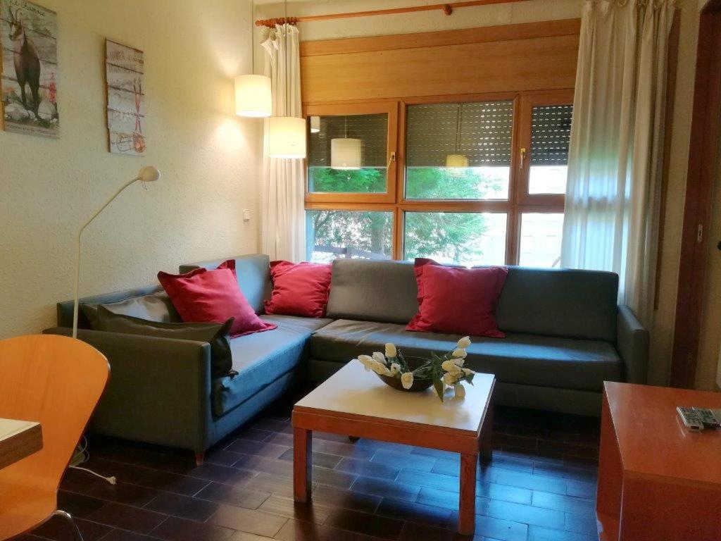 a living room with a blue couch with red pillows at Multipropiedad Baqueira 1500 in Baqueira-Beret
