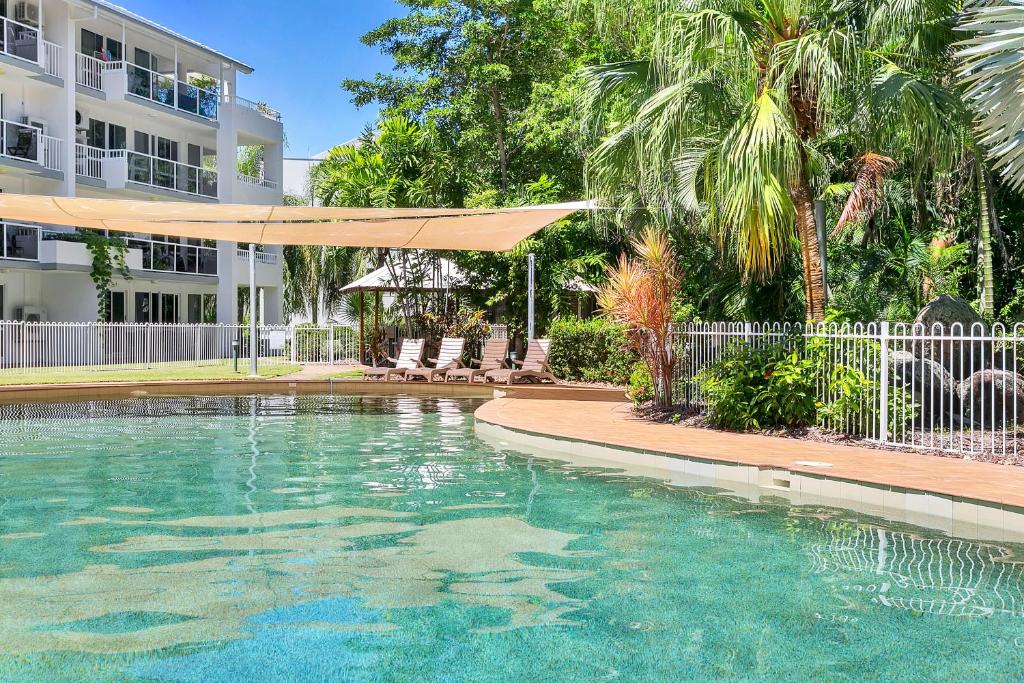 a swimming pool in front of a building at Coral Coast Resort Apartment in Palm Cove