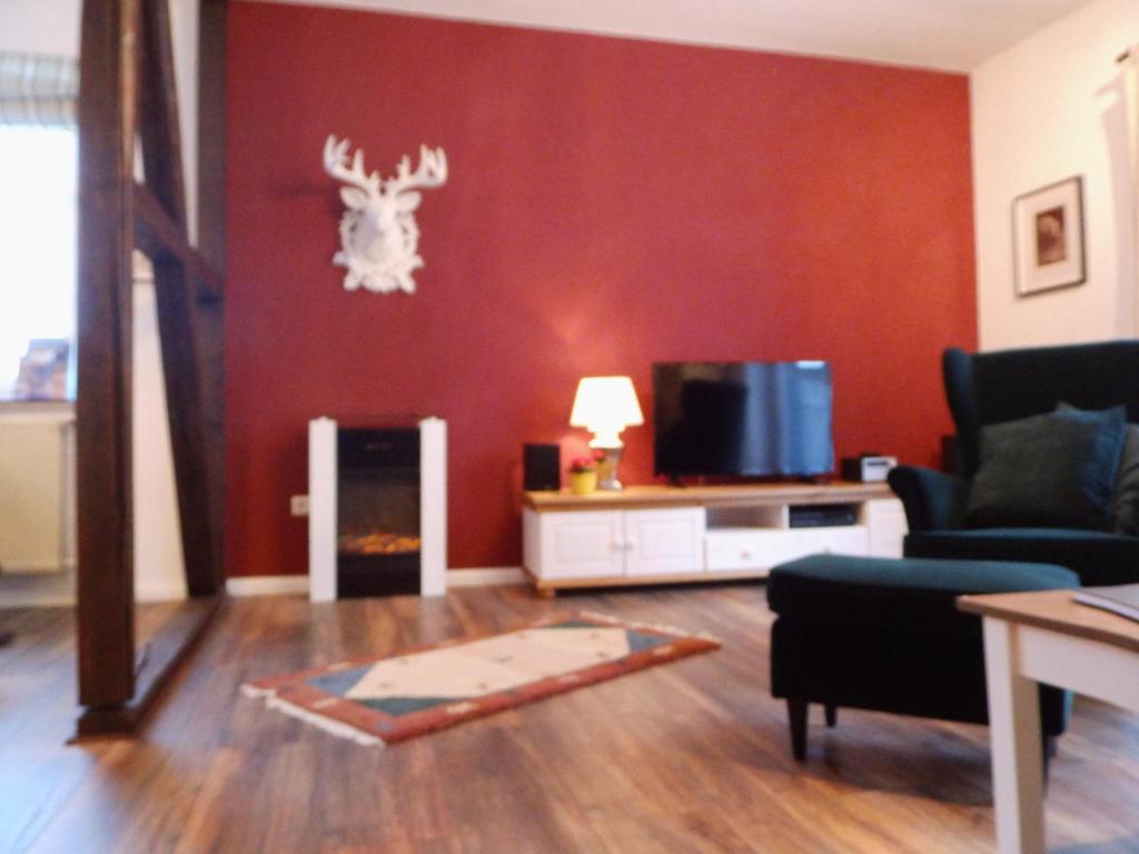 ein Wohnzimmer mit einer roten Wand mit einem Hirschkopf an der Wand in der Unterkunft Harzglück in Hahnenklee-Bockswiese
