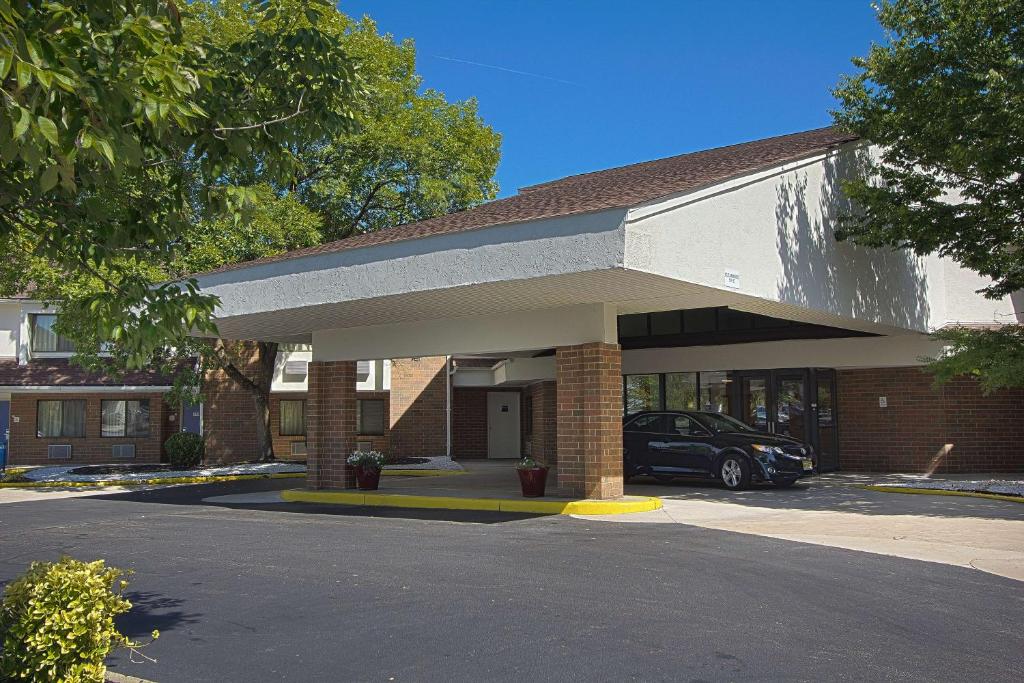 um edifício com um carro estacionado num parque de estacionamento em Motel 6-East Brunswick, NJ em East Brunswick