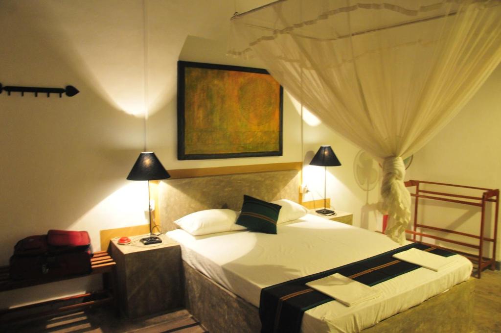 a bedroom with a large bed and a curtain at Waters Edge, Anuradhapura in Anuradhapura