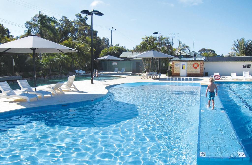 a boy standing in the water in a swimming pool at Karrinyup Waters Resort in Perth