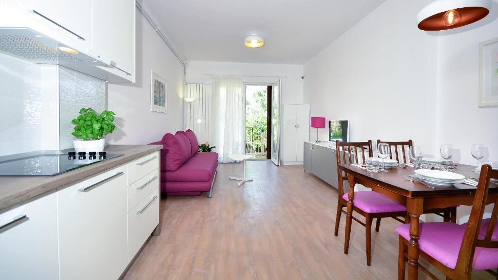 een keuken en eetkamer met een tafel en paarse stoelen bij Apartments Denise in Podgora