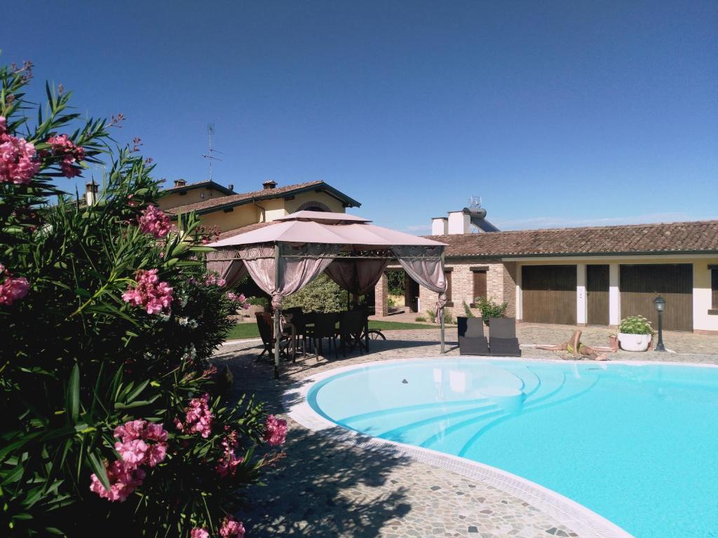 una piscina con sombrilla y una casa en B&B Il Martin Pescatore en Bagnolo San Vito