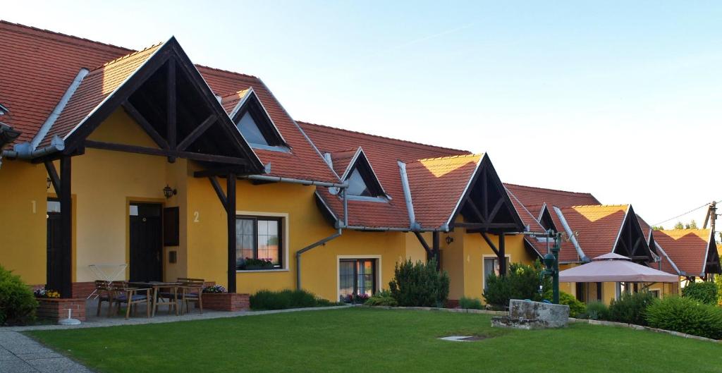 una casa amarilla con techos marrones y un patio en Huber Panzió, en Fertőrákos