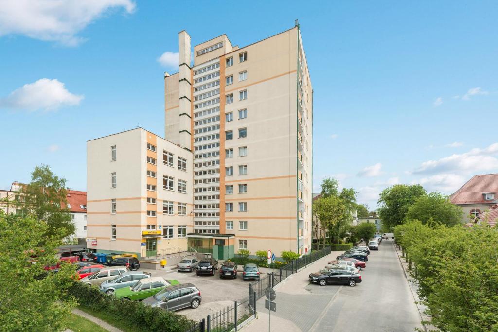 a tall building with cars parked in a parking lot at Apartament z widokiem na morze in Sopot