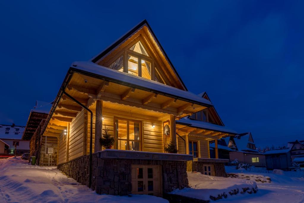 une maison en rondins dans la neige la nuit dans l'établissement Zacisze Galicove, à Zakopane