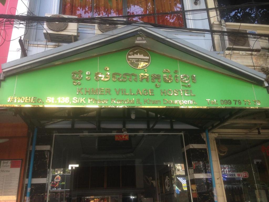 zielony znak na przedniej części budynku w obiekcie Khmer Village Guesthouse w mieście Phnom Penh