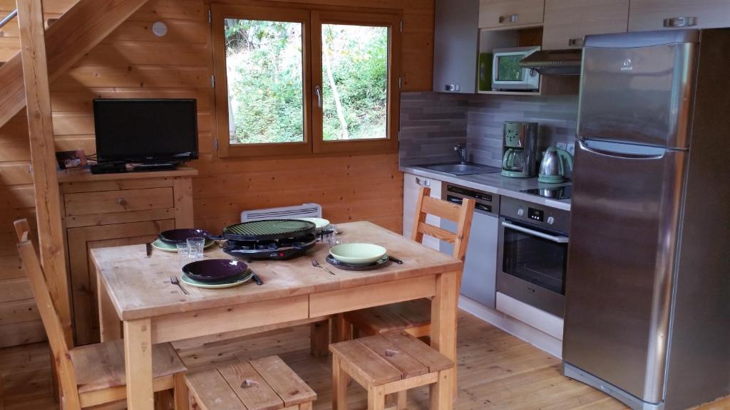 eine Küche mit einem Holztisch, einem Herd und einem Kühlschrank in der Unterkunft La cabane du pommier in Orelle