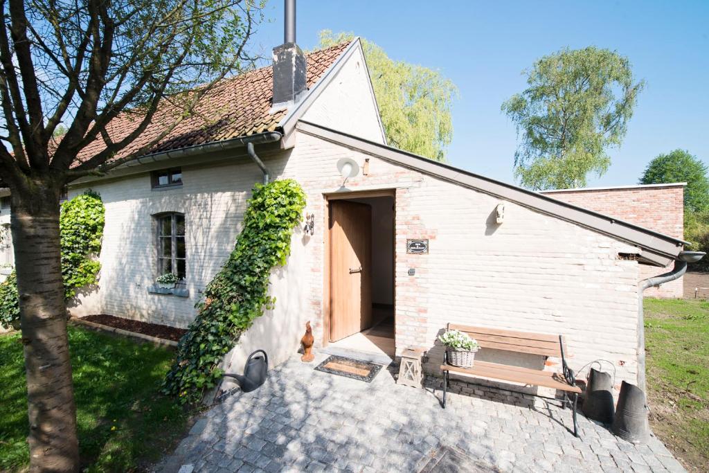 a small white building with a dog sitting in front of it at B&B De Hanewijkhoeve in Werchter