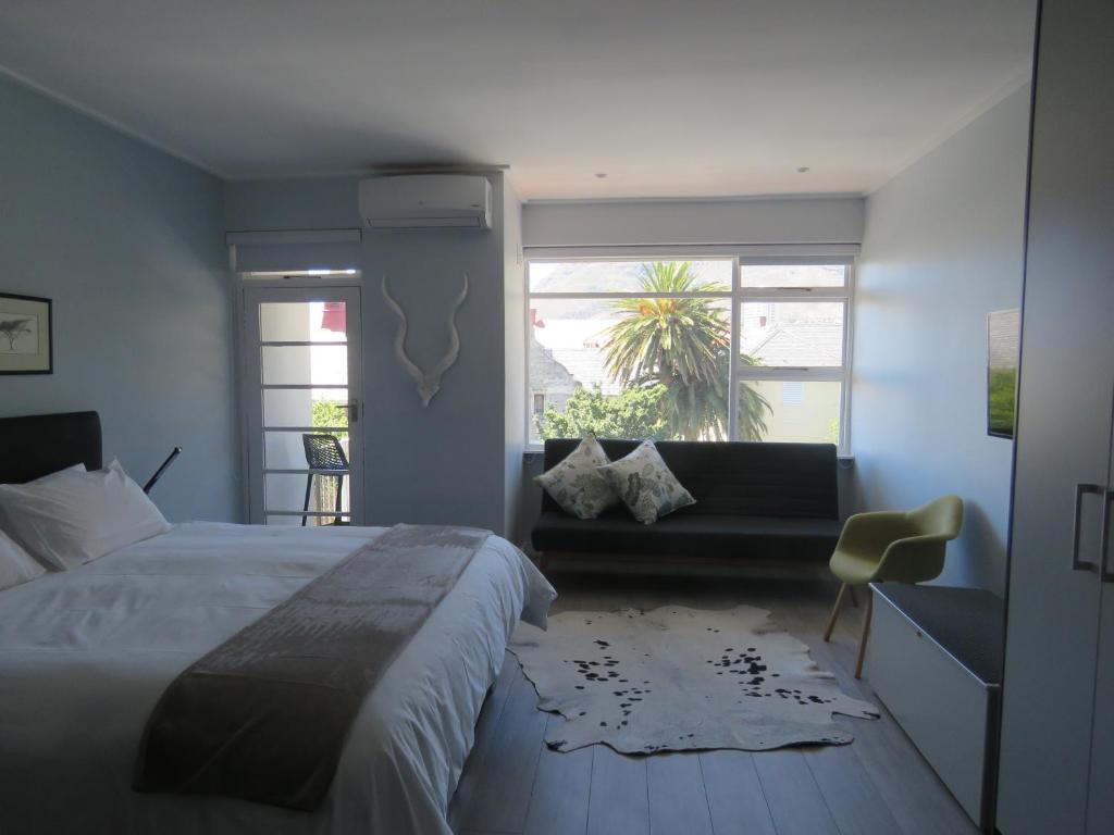 um quarto com uma cama, um sofá e uma janela em Oranjehof Studios em Cidade do Cabo