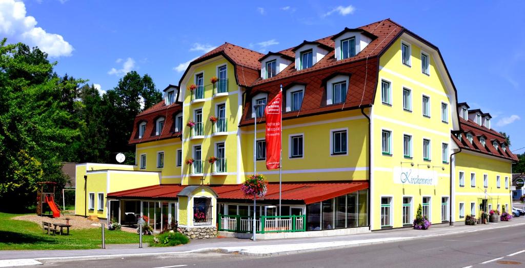 ein großes gelbes Gebäude mit rotem Dach in der Unterkunft Hotel-Restaurant Kirchenwirt Aigen in Aigen im Ennstal