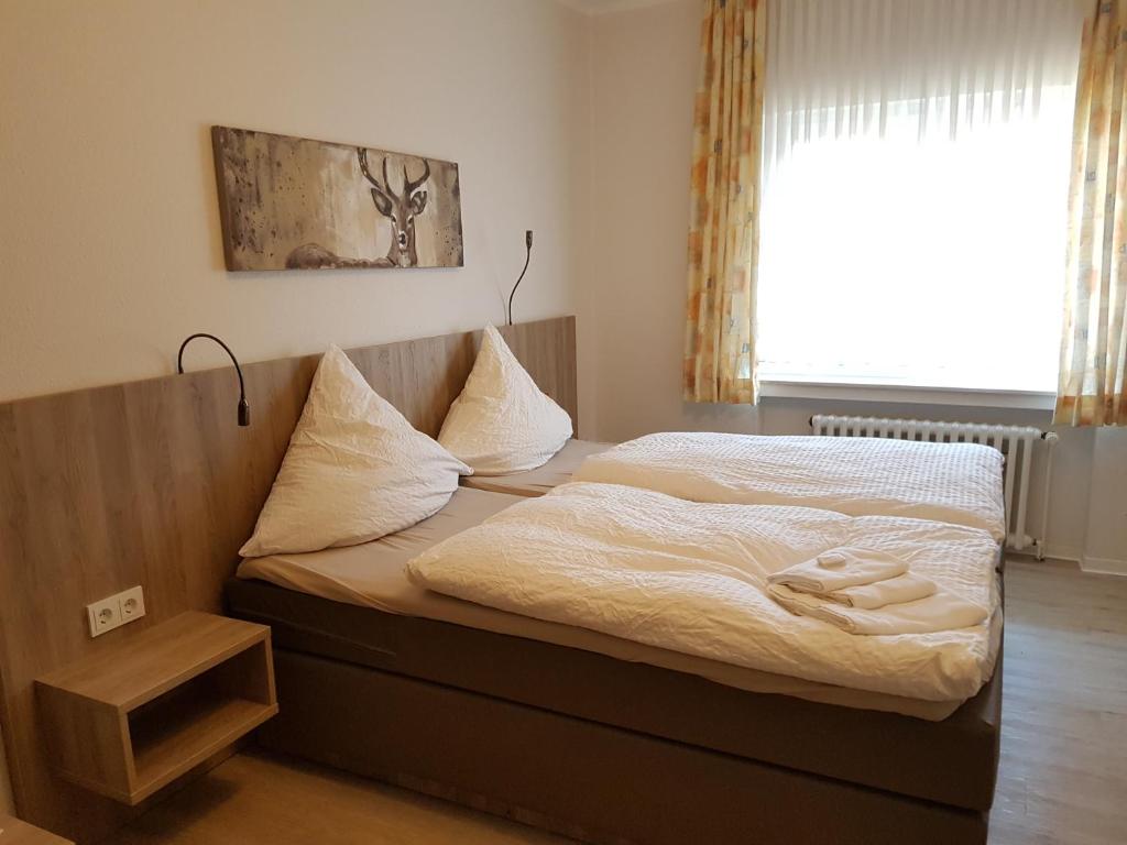 a bedroom with a bed with white sheets and a window at Hotel Pension Haus Pooth in Wesel