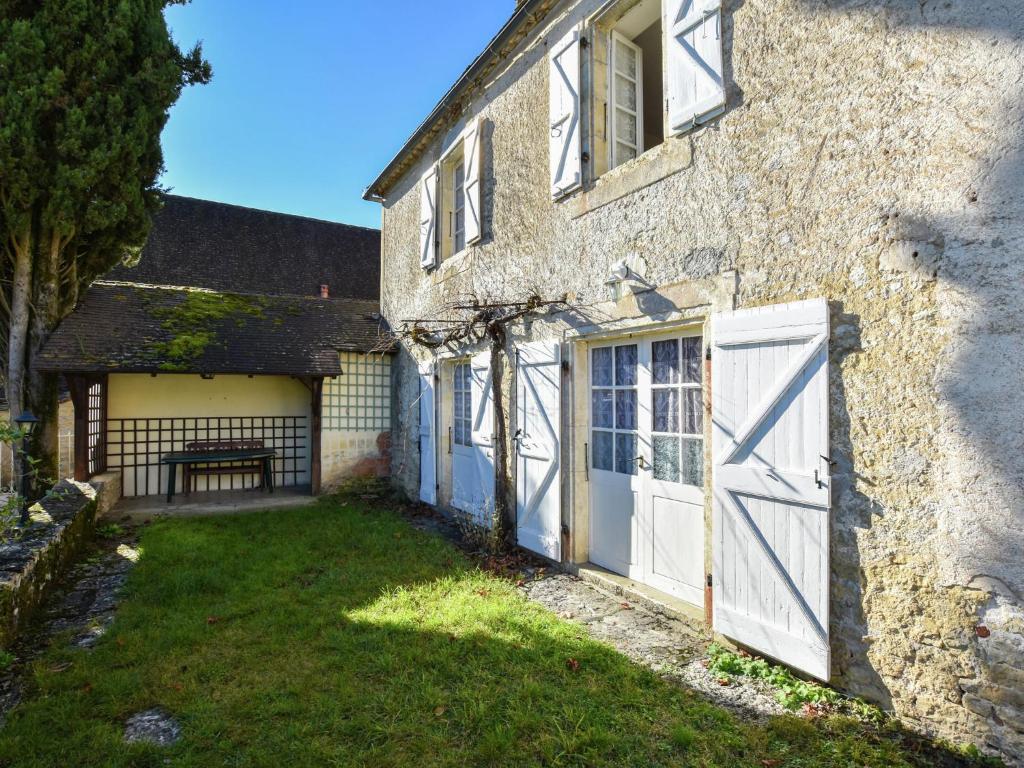 an old stone house with white doors and a yard at Beautiful holiday home near the forest in Labastide-Murat