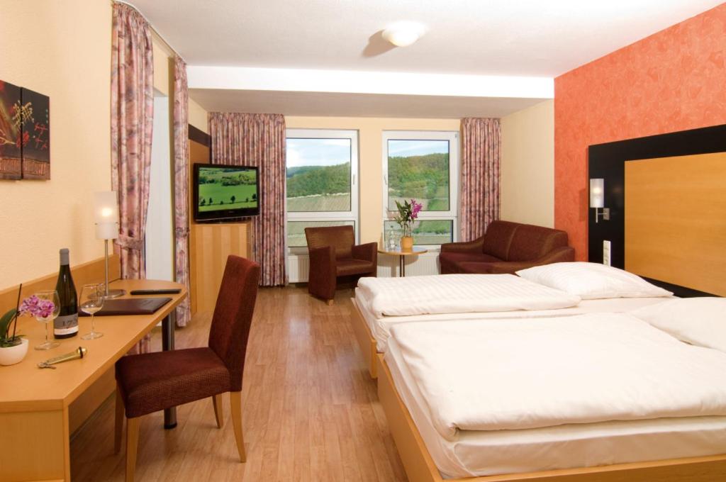 ein Hotelzimmer mit einem Bett und einem Schreibtisch in der Unterkunft Burg-Hotel in Obermoschel