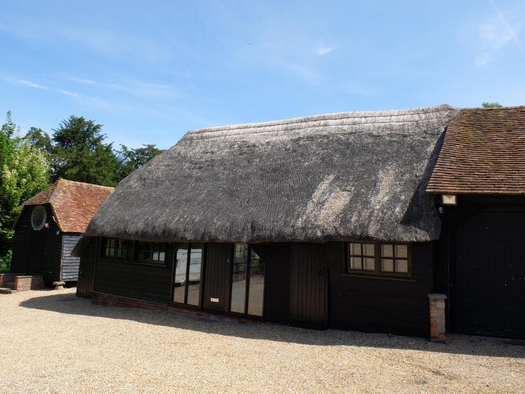 een zwarte schuur met een rieten dak bij The Thatched Barn in Thame